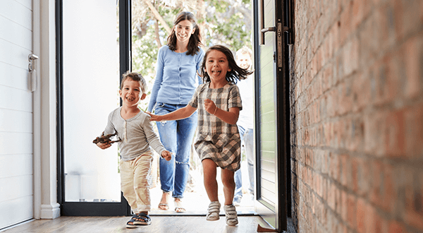 A mother and two children joyfully entering their home stock photo